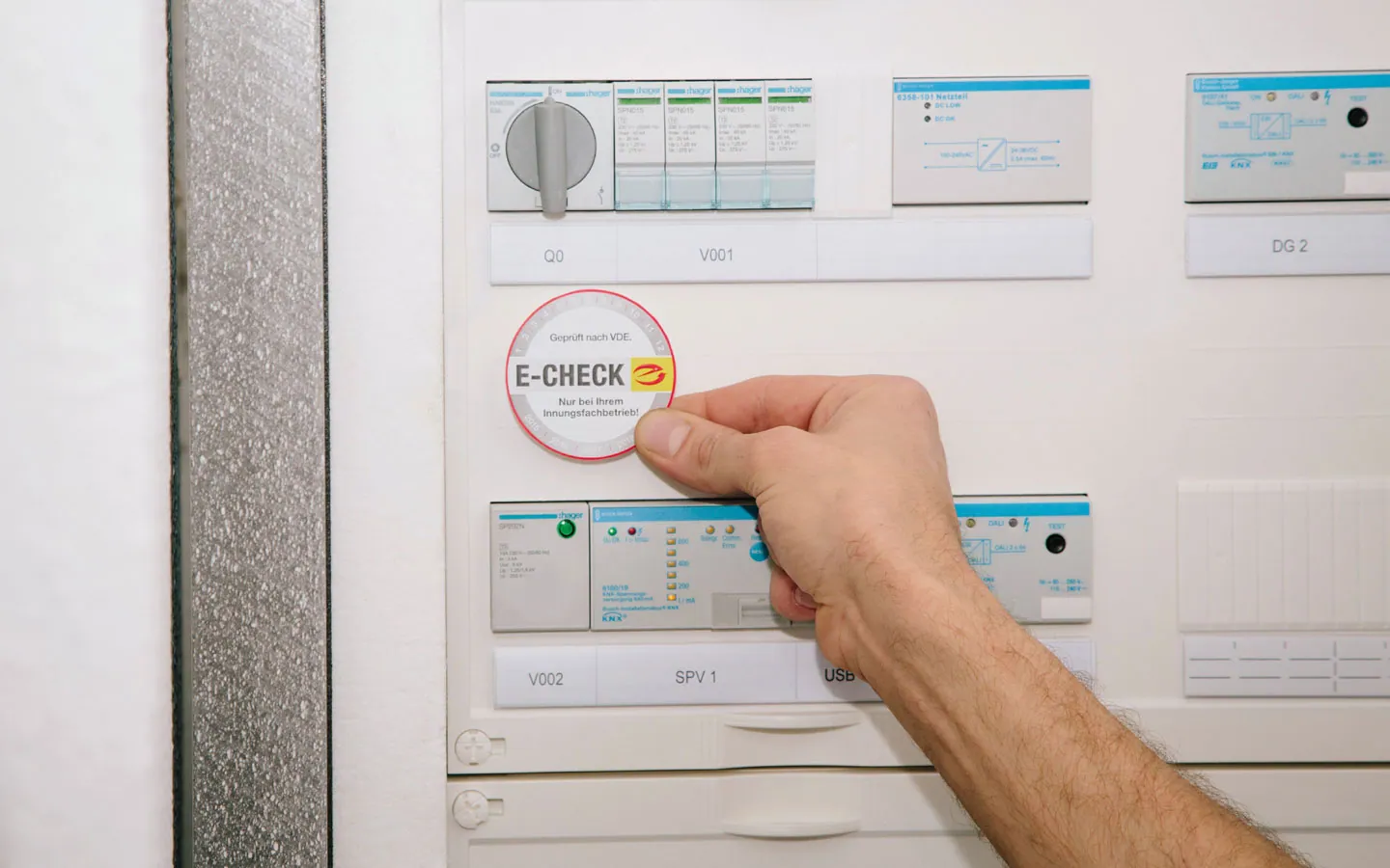 E-CHECK - Mitarbeiter klebt in der Verteilung die E-CHECK Plakette an &middot; Elektro Dörr