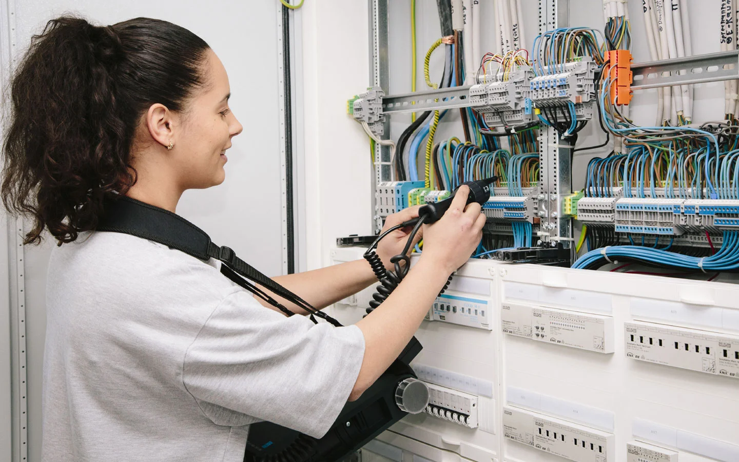 E-CHECK - Mitarbeiterin prüft im Schaltschrank mit einem Meßgerät &middot; Elektro Dörr