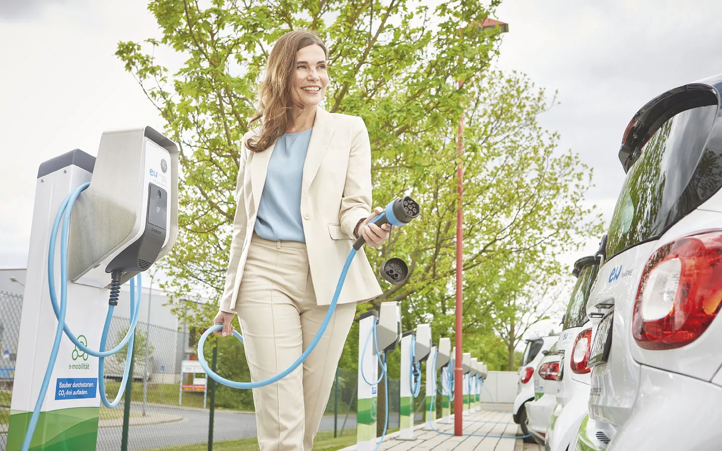 E-Mobilität - Kundin vor Ladestation mit Stecker in der Hand &middot; Elektro Dörr